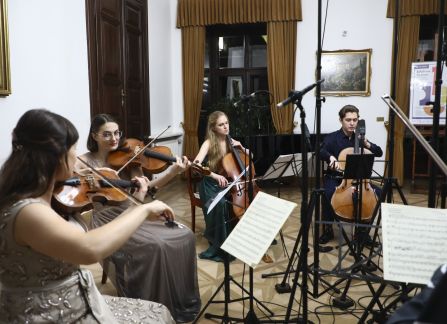 A photograph. A string concert in Villa Decius. The musicians play the violin and the cello in the Ball Room at Villa Decius.